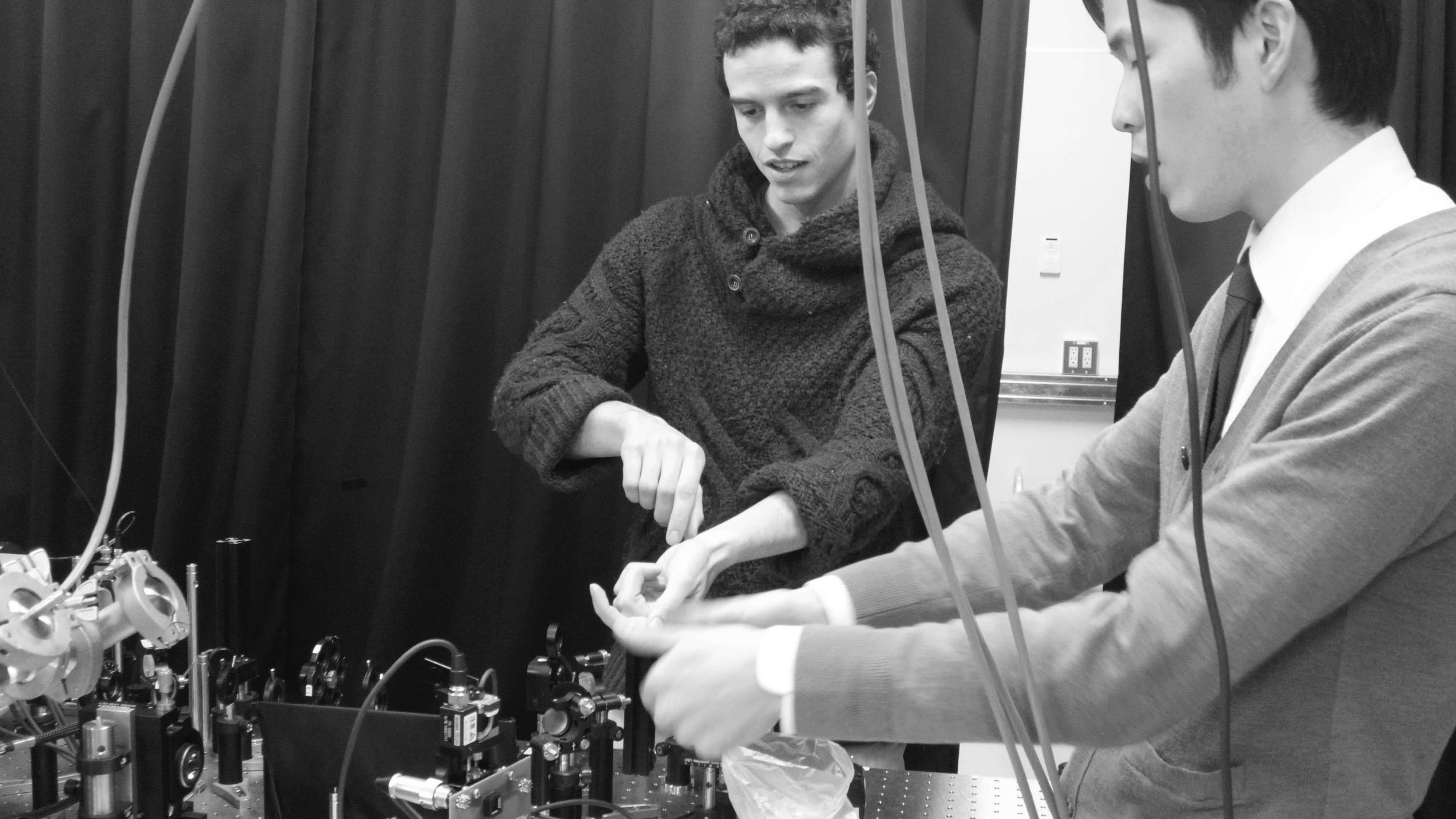 two researchers aligning an optical experiment in a laboratory