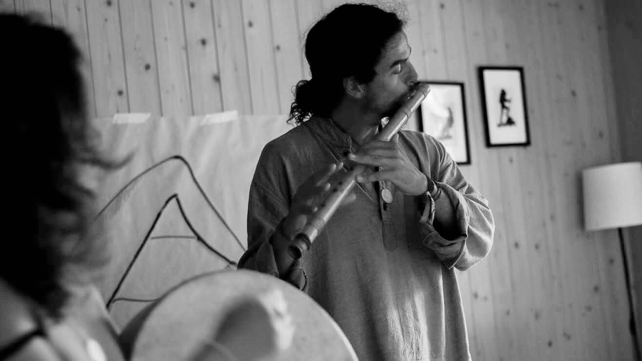 playing a bansuri flute, eyes closed, mid-performance