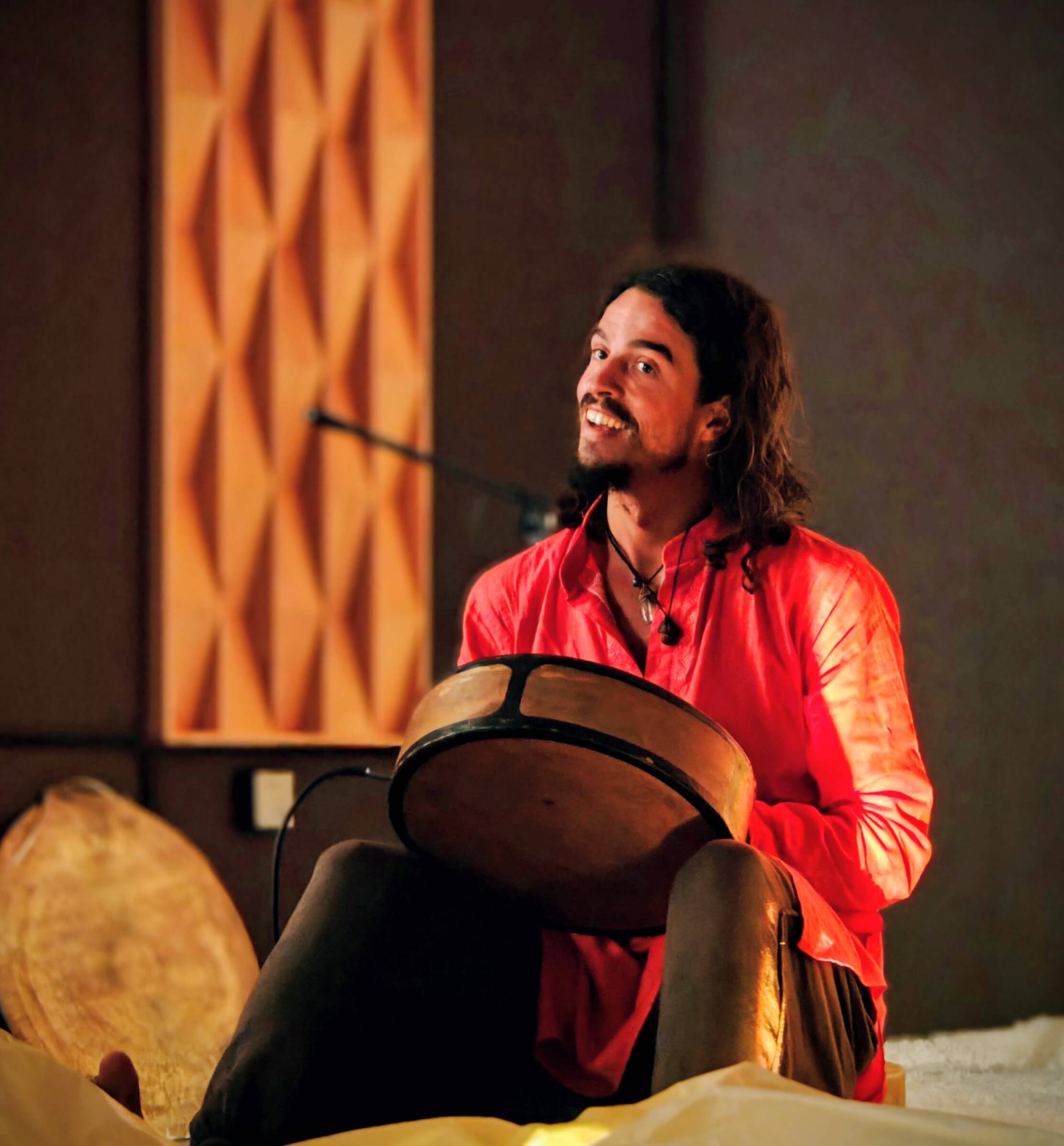 alexander popert, smiling, seated behind a frame drum